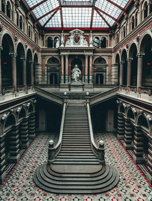 Scalinata monumentale in un palazzo con statue e architettura storica, dettagli architettonici e pavimento decorato